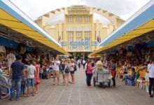 The iconic yellow Art Deco dome of Central Market (Psar Thmei) in Phnom Penh, Cambodia, with the bustling street and market entrance visible below