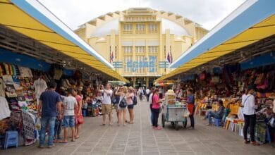 The iconic yellow Art Deco dome of Central Market (Psar Thmei) in Phnom Penh, Cambodia, with the bustling street and market entrance visible below