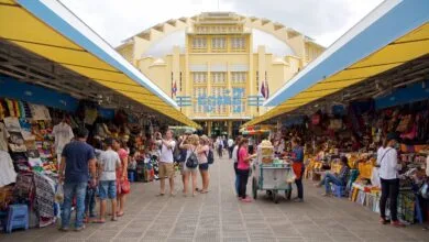 The iconic yellow Art Deco dome of Central Market (Psar Thmei) in Phnom Penh, Cambodia, with the bustling street and market entrance visible below