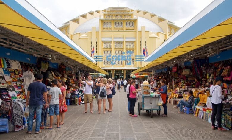 The iconic yellow Art Deco dome of Central Market (Psar Thmei) in Phnom Penh, Cambodia, with the bustling street and market entrance visible below