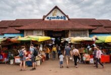 The yellow-and-white exterior of Phsar Leu Thom Tmey market building on National Road 6 in Siem Reap, Cambodia