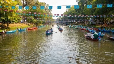 Riverside buildings, trees and a small bridge along the Siem Reap River in Cambodia at dusk