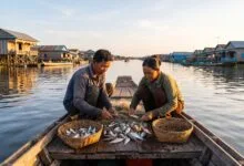 A Cambodian fishing family sorting their catch on a wooden boat on Tonlé Sap Lake in the early morning.