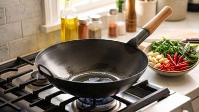 YOSUKATA 14-inch black carbon steel wok with round bottom on a gas stove.