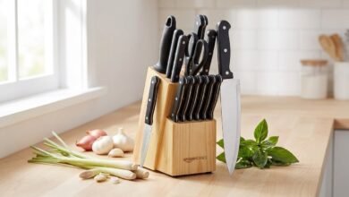 Amazon Basics 14-piece kitchen knife set with pinewood block, chef's knife, paring knife, and other knives on a kitchen counter with fresh herbs and aromatics.