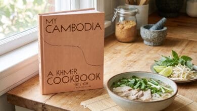My Cambodia: A Khmer Cookbook by Nite Yun displayed on a kitchen counter with a bowl of Cambodian noodle soup nearby