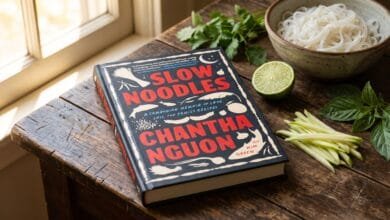 Slow Noodles: A Cambodian Memoir of Love, Loss, and Family Recipes book cover on a wooden kitchen table with fresh ingredients