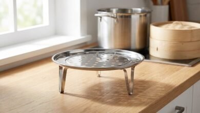 Round stainless steel steamer rack with detachable legs on a kitchen counter, with a stock pot in the background.