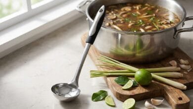 Zulay Kitchen 12-inch stainless steel soup ladle standing on a kitchen counter next to a pot of soup.